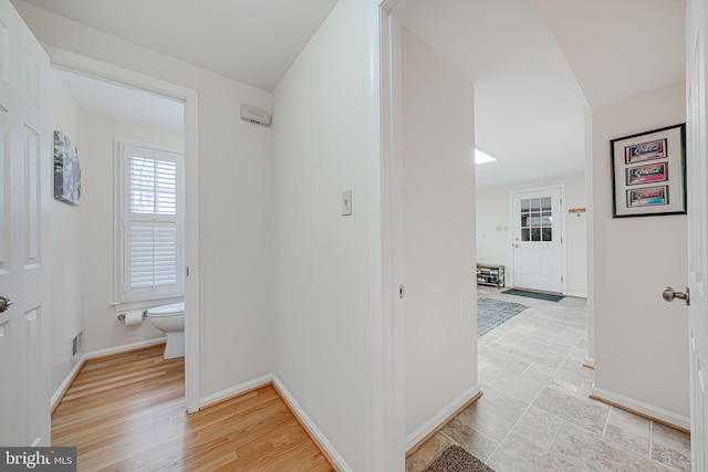 corridor featuring visible vents, baseboards, and light wood-style flooring