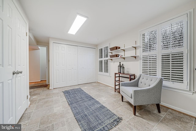 living area featuring baseboards and stone tile flooring