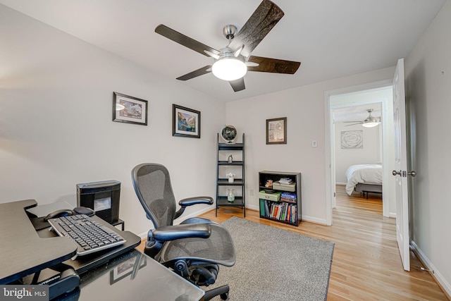 office area featuring baseboards, light wood-type flooring, and a ceiling fan