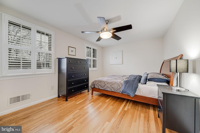 bedroom with visible vents, baseboards, light wood-style flooring, and a ceiling fan