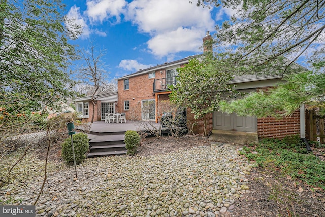 back of property with brick siding, a deck, and a balcony