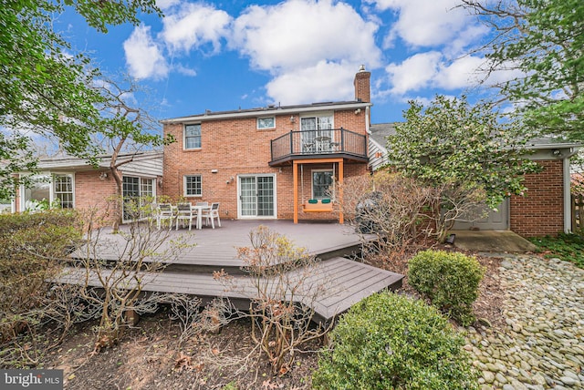 back of property featuring a balcony, outdoor dining area, brick siding, and a chimney