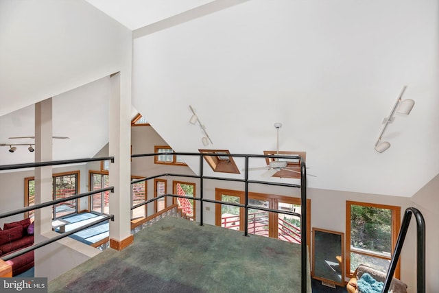 stairway with lofted ceiling and track lighting