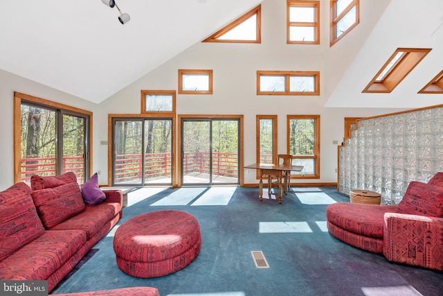 carpeted living room with visible vents, high vaulted ceiling, and baseboards