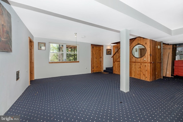 basement featuring carpet flooring, wood walls, and stairway