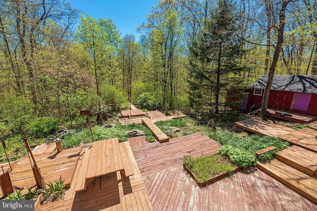 deck featuring an outbuilding, a wooded view, and a shed