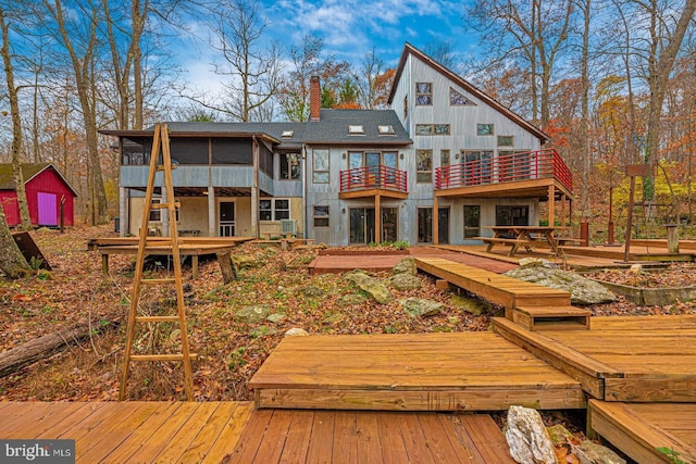 back of house featuring an outbuilding, a chimney, and a sunroom