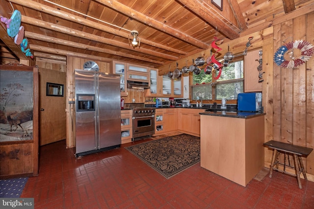 kitchen with a peninsula, wooden walls, under cabinet range hood, and stainless steel appliances