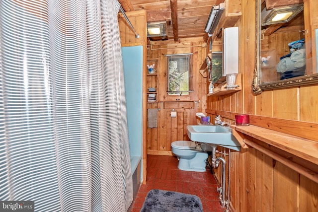 bathroom featuring wood walls, toilet, shower / tub combo, and a sink