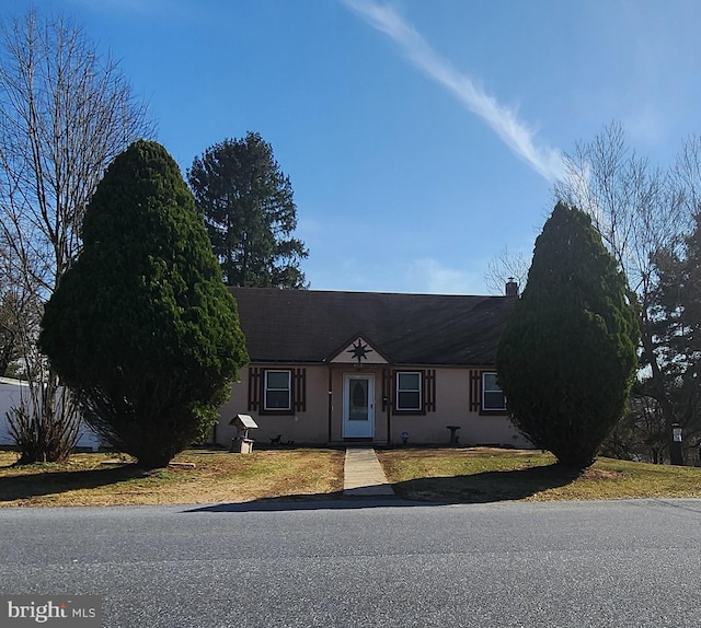 view of front of house featuring stucco siding, a front lawn, and roof with shingles