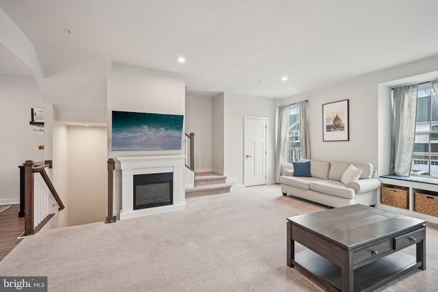 living area with baseboards, carpet, stairs, recessed lighting, and a glass covered fireplace