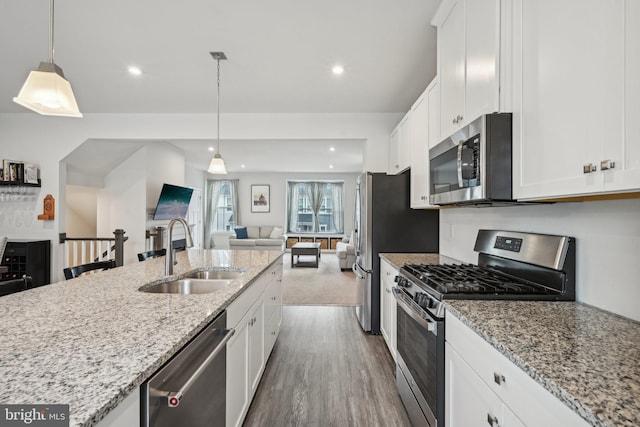 kitchen featuring a sink, stainless steel appliances, dark wood-type flooring, white cabinetry, and open floor plan