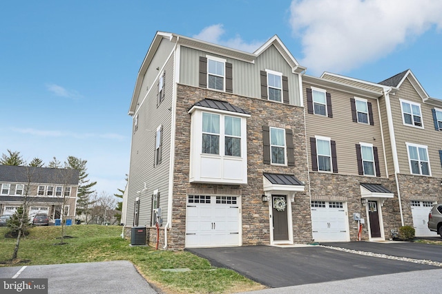 multi unit property with driveway, stone siding, board and batten siding, a garage, and central AC unit