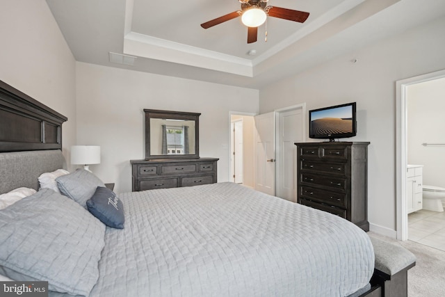 bedroom with visible vents, baseboards, a tray ceiling, ensuite bathroom, and light colored carpet