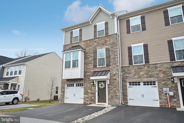 view of property with aphalt driveway, stone siding, board and batten siding, and a garage