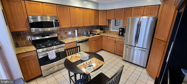 kitchen featuring brown cabinetry, light tile patterned floors, appliances with stainless steel finishes, and decorative backsplash