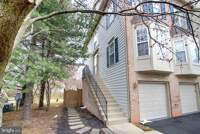 view of side of property with stairway, a garage, and brick siding