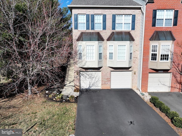 multi unit property featuring brick siding, driveway, and a garage