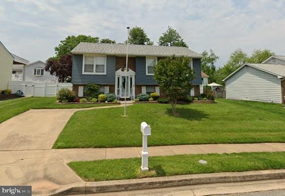 bi-level home with a front lawn and fence