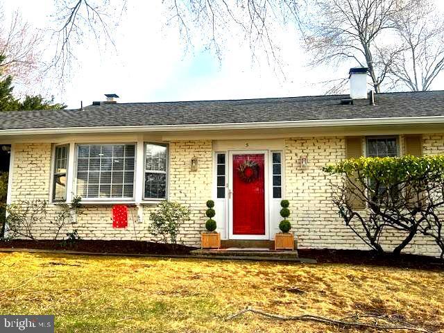 view of exterior entry with a yard, brick siding, and roof with shingles