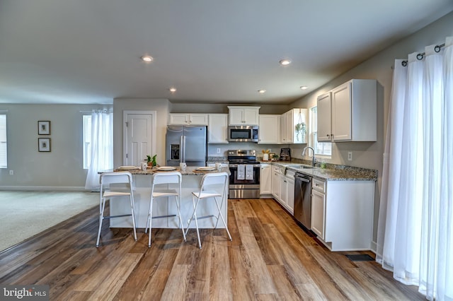 kitchen with a sink, plenty of natural light, a kitchen island, and appliances with stainless steel finishes