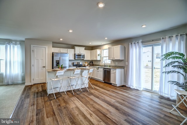 kitchen with a kitchen island, recessed lighting, dark wood-type flooring, appliances with stainless steel finishes, and white cabinetry