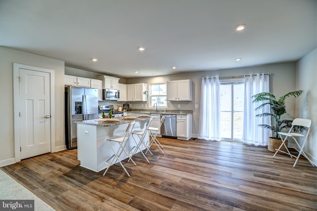 kitchen featuring a sink, dark wood finished floors, a center island, white cabinetry, and appliances with stainless steel finishes
