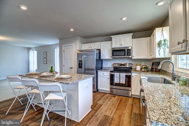 kitchen featuring light wood-type flooring, recessed lighting, appliances with stainless steel finishes, white cabinetry, and a sink