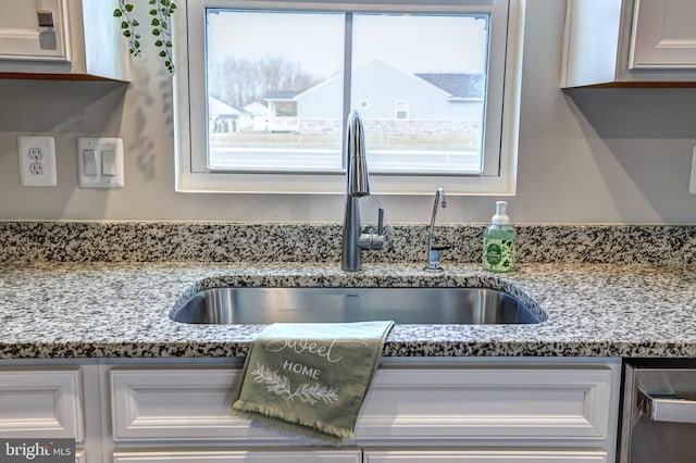 details with white cabinets, light stone countertops, and a sink