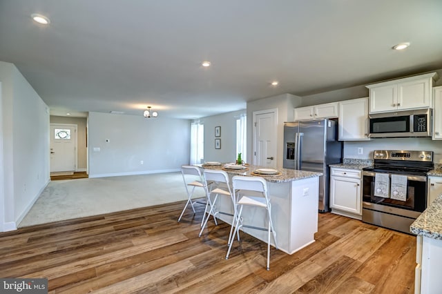 kitchen featuring a center island, open floor plan, light wood-style flooring, appliances with stainless steel finishes, and white cabinets