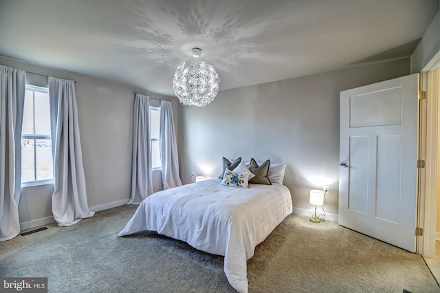 carpeted bedroom featuring a chandelier and baseboards