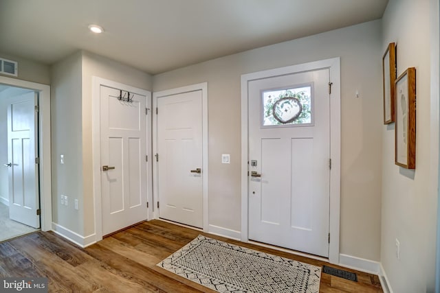foyer with visible vents, wood finished floors, and baseboards
