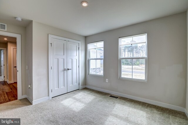 unfurnished bedroom featuring a closet, baseboards, visible vents, and carpet flooring