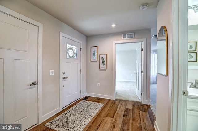 entrance foyer with wood finished floors, visible vents, and baseboards