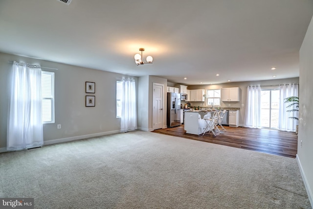unfurnished living room featuring recessed lighting, baseboards, an inviting chandelier, and carpet floors