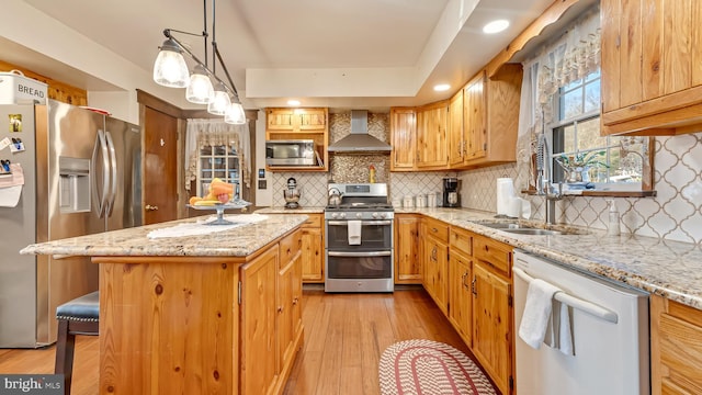 kitchen featuring light wood-type flooring, a sink, tasteful backsplash, stainless steel appliances, and wall chimney range hood