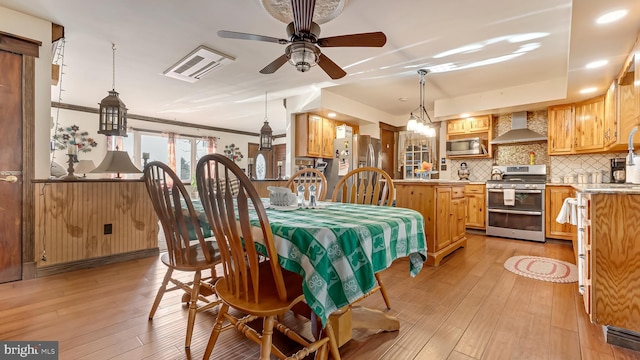 dining room with light wood-style flooring, crown molding, and ceiling fan