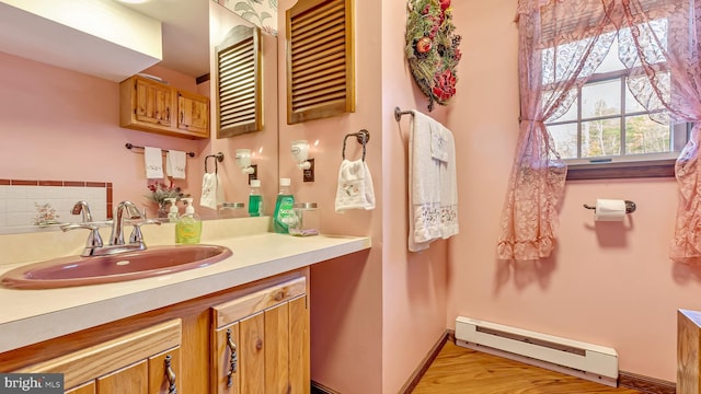 bathroom with vanity, wood finished floors, baseboards, and a baseboard radiator