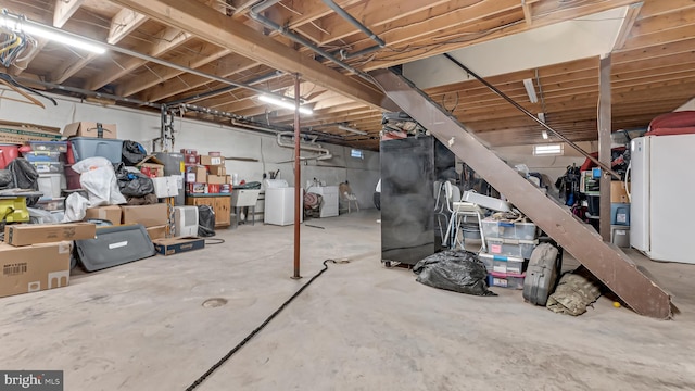 unfinished basement with washer / dryer and freestanding refrigerator