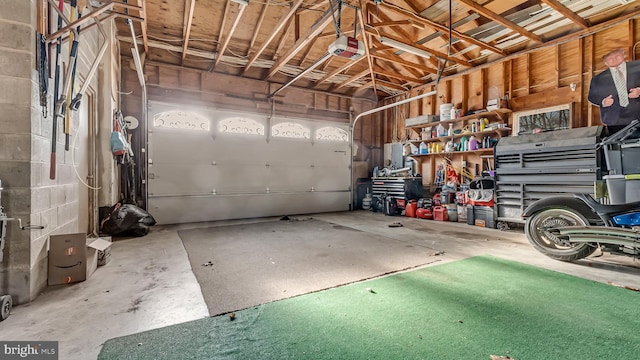 garage featuring concrete block wall and a garage door opener