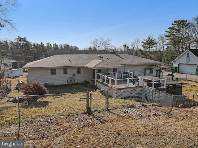 back of property with an outbuilding, a gate, fence, roof with shingles, and a deck