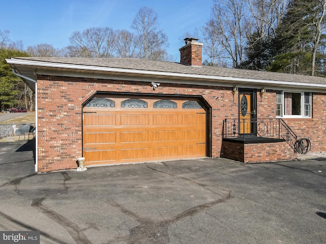 exterior space with brick siding, a chimney, aphalt driveway, and a garage