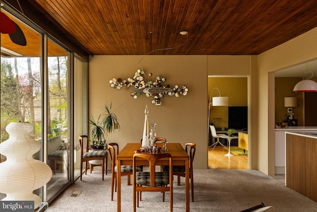 dining room featuring light colored carpet, wooden ceiling, and expansive windows