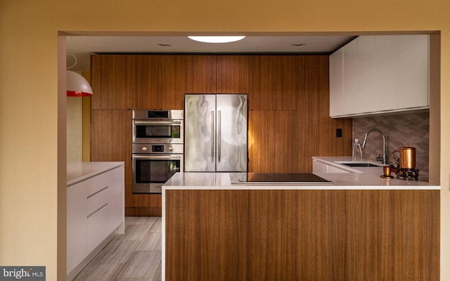 kitchen with backsplash, modern cabinets, brown cabinets, a sink, and stainless steel appliances