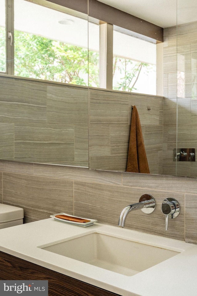 bathroom with vanity, decorative backsplash, toilet, and tile walls