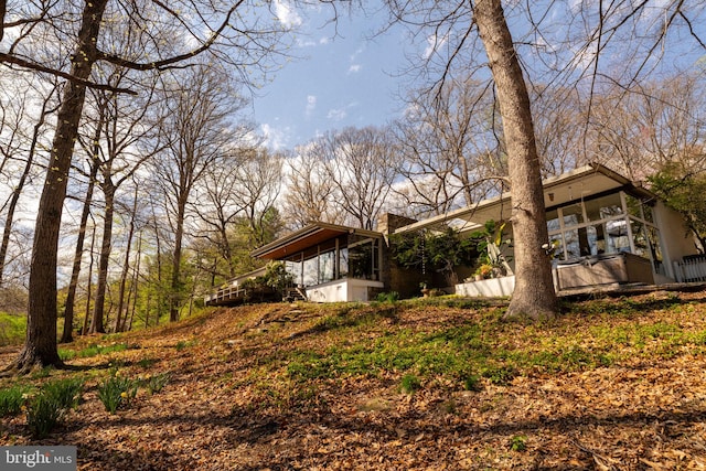 view of side of home featuring a sunroom and a chimney