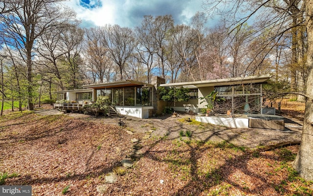 back of property with a sunroom and a chimney