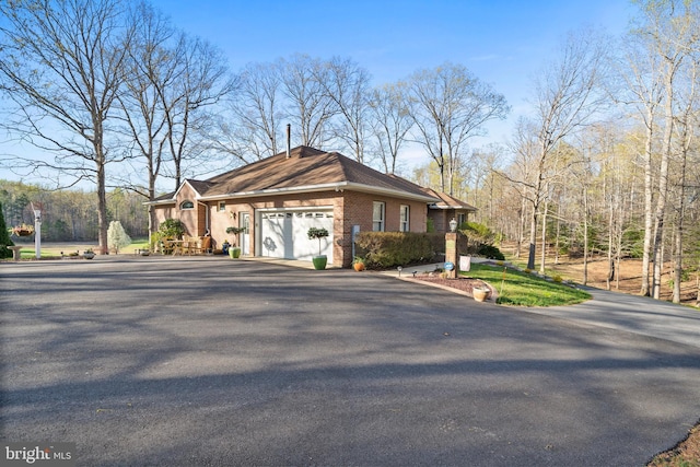 view of front facade featuring brick siding, an attached garage, and aphalt driveway