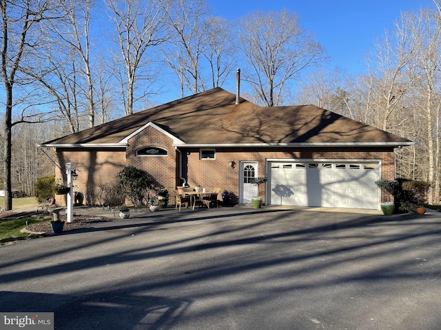 ranch-style home featuring a garage, driveway, and brick siding