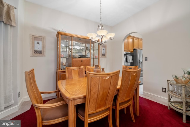 dining area with arched walkways, an inviting chandelier, dark carpet, and baseboards